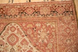 Corner detail of an antique Farahan Sarouk rug showing dusty rose floral palmettes and mostly even wear to knot heads.