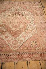 Angled view of a Farahan Sarouk rug showing its shield-like medallion, worn pile, and ivory spandrels.