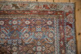 Distressed vintage Northwest Persian rug corner with blue, terracotta, beige Herati motifs.