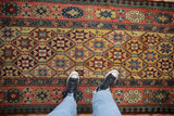 Lattice field of starburst motifs and a floral top-view border on an antique Kazak runner.