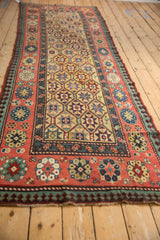 Long perspective view of an antique Caucasian Kazak runner, showing its geometric starburst field and intricate borders.