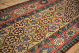 Close view of starburst geometric panels and floral borders on an antique Caucasian Kazak rug.