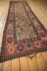 A long antique Kazak runner viewed from an angle, highlighting its rich, geometric Caucasian design.
