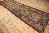 Angled perspective of an antique Caucasian Kazak runner, showing its full length and intricate geometric pattern.