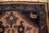 Detail of a vintage Mehreban rug corner with floral palmettes in the camel and dark navy borders.