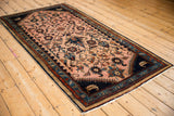 Angled view of the vintage Persian Mehreban runner's floral pattern and dark navy border.