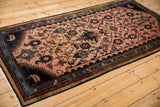 Angled view of a vintage Mehreban runner showing its elaborate floral design and rich navy blue border.