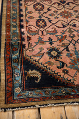 Corner detail of a vintage Persian rug showing the camel border and floral navy arabesques.