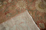 A folded corner of a distressed Mahal carpet reveals the hand-knotted weave and low pile.
