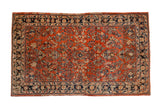 Vintage Persian Sarouk carpet with floral sprays on a brick red field and a navy blue lotus motif border.