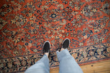 Dense floral sprays in navy, sand, and blue across the hand-knotted, brick-red pile of a vintage Sarouk.