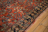 Intricate navy blue floral border and brick red field of a vintage Persian Sarouk carpet.