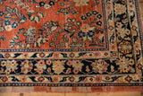 Corner detail of a vintage Sarouk showing the lotus flower border against the brick red field.