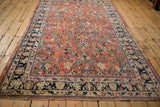 Angled perspective on a vintage Sarouk carpet showing the full floral design and navy border.