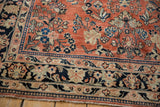 Angled view of a vintage Sarouk corner showing the floral main border and low pile.