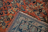 A folded corner reveals the hand-knotted back and floral pile of a vintage Persian Sarouk carpet.