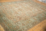 Angled view across the length of a distressed Ghiordes carpet highlighting its time-softened floral pattern.