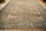 Angled perspective down the length of a distressed Ghiordes carpet showing its allover floral design.