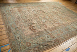 Full angled view of a distressed Ghiordes carpet showing its allover floral pattern in dusty earth tones.