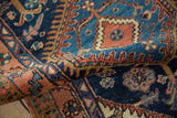 Vintage Heriz rug's textured pile, with cobalt blue, madder red, and gold serrated patterns.