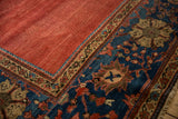 Striated cochineal red field meets sapphire border with intricate palmettes on antique Sultanabad rug.
