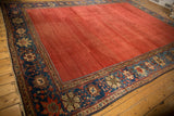 Striated cochineal red field meeting a sapphire blue palmette border on an antique Sultanabad.