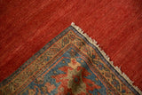 Antique Persian Sultanabad rug corner, revealing striated ruby red field, fringed edge, and sapphire blue motifs.