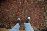 Antique Qashqai rug with chestnut field, allover geometric pattern, and scattered bird motifs.