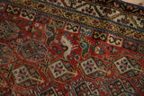Antique Qashqai rug detail: germinating shrub motif, birds, and border in chestnut, blue, ivory.