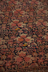 Even wear across antique Malayer rug's dusty blush, navy, and ivory floral knot heads.