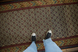 Intricate geometric lattice and colorful border of an antique Caucasian runner shown from above for scale.