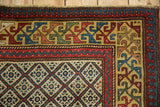 The ivory lattice field meets the intricate, colorful geometric border of an antique Caucasian rug.