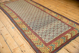 Angled view of an antique Caucasian runner highlighting the geometric lattice field and colorful border.