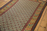 Angled view of an antique Caucasian runner's geometric lattice pattern and richly colored main border.