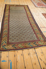Angled view of an antique Caucasian runner's intricate geometric border and repeating lattice field.