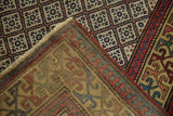Folded corner revealing the hand-knotted construction and back of an antique Caucasian lattice rug.