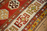 Angled view of an antique Kazak runner's border with stylized rams horn guls on an ivory ground.