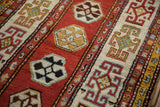 Close view of the knot heads and time-softened dark wool on an antique Kazak rug.
