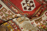 Time-softened tones and wool texture of a draped antique Caucasian Kazak rug with geometric guls.