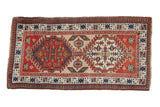 Vintage Serab rug runner with two geometric medallions and a pawn design border in red, teal, and beige.