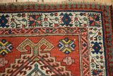 Corner of a vintage Persian Serab rug highlighting its geometric pawn design border in red, blue, and sand.