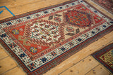 Angled view of a vintage Persian Serab runner with bold geometric medallions and tattered sides.