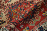 A vintage Serab rug folded over, revealing the intricate, hand-knotted pawn design in red, teal, and sand.