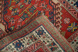 Folded corner of a vintage Serab rug displaying the red pile and detailed hand-knotted foundation.