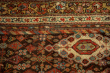 Antique Hamadan rug's madder red floral border, dusty green vine detail, and ivory diamond medallion.