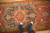 Scale view of an antique Heriz runner's large medallion with red, navy, and ochre tones.