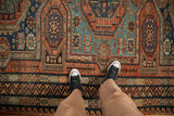 Overhead view of an antique Soumac carpet's red and blue triple gul medallion and geometric borders.