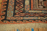 Antique Soumac carpet corner showing geometric zig-zag and wave borders with its original macrame fringe.