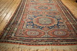 Angled view down the length of an antique Soumac carpet, highlighting its repeating geometric gul medallions.