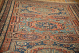 Angled view of repeating gul medallions and complex serpent borders on an antique Soumac carpet.